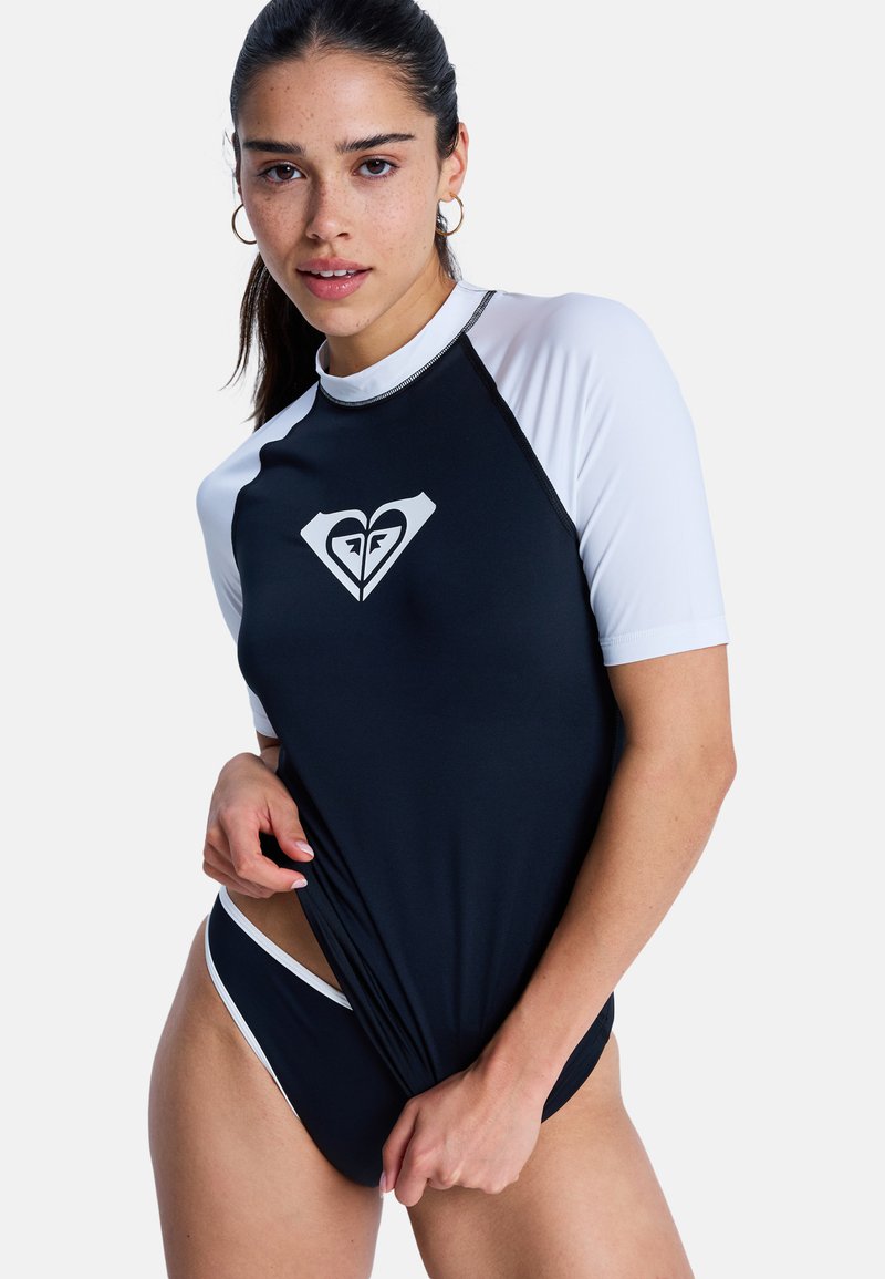 Protection anti-éruption à manches courtes noire et blanche avec un logo, offrant une coupe ajustée et une texture lisse, idéale pour les activités nautiques.