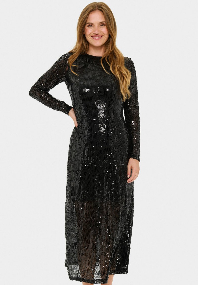 Rochie lungă cu mâneci lungi, din paiete negre, cu o siluetă ajustată, lungime medie a hămului și o textură netedă, lucioasă, care reflectă lumina.