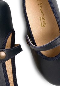 Black leather shoes with a rounded toe, a strap across the instep, and a button closure. Interior features light tan textured lining.