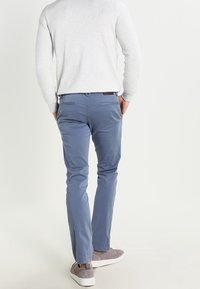 Ljusblå slim-fit byxor i blandad bomull, med bakfickor och tillsammans med grå mockaskor.