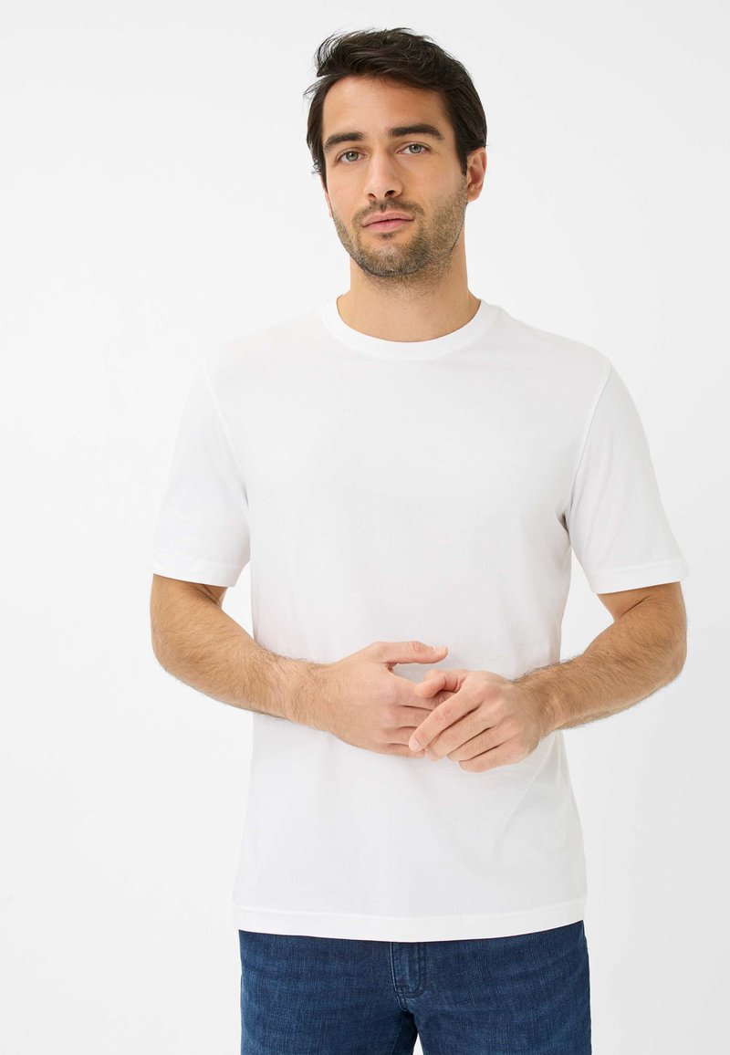 T-shirt in cotone bianco con maniche corte, collo rotondo e vestibilità comoda. Design minimalista; presenta una texture liscia e un dettaglio sui bordi discreto.