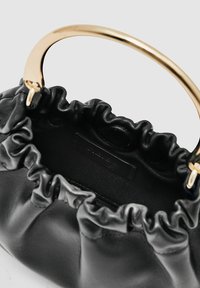 Sort læderhåndtaske med et håndtag af guldmetal. Designet har en rynket åbning og et tekstureret indre, hvilket giver en kompakt form.