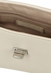 Interno di un portafoglio in pelle crema con una texture liscia, presenta una fodera in tessuto marrone, una tasca con zip e una chiusura in metallo argentato.