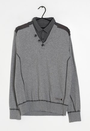 Sudadera gris de manga larga con cuello en V, que presenta acentos oscuros en los hombros, una tapeta de tres botones y dobladillo texturizado. Detalles de costura horizontal.