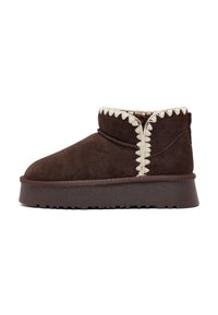 Bruine suède enkelboot met een ronde neus, een geprofileerde zijsam en crèmekleurige decoratieve stiksels. Heeft een lage platformzool met grip.