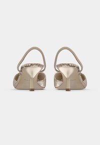 Sandales à talons hauts beiges avec accents en faux motif serpent, dos ouvert et fines lanières, dotées d'un talon élancé et d'une surface texturée.