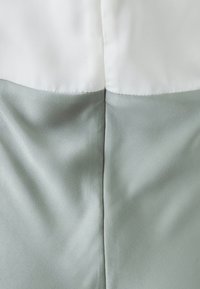 Dwukolorowy ubiór z białą górną częścią i jasnobłękitną dolną częścią. Gładka tekstura, połączony płaskim szwem na środku.