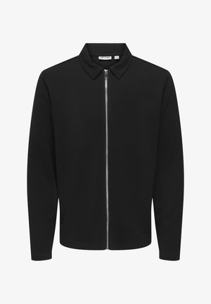 Chaqueta negra con cremallera y cuello, con mangas largas, un tejido texturizado y un cierre de cremallera plateada en el centro delantero.