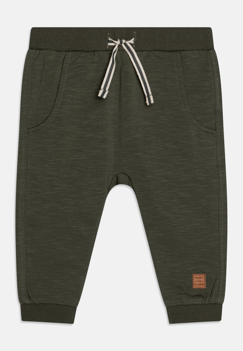 Jogging en coton vert foncé avec taille élastique et cordon de serrage. Présente deux poches latérales et une petite étiquette de marque sur la jambe gauche.