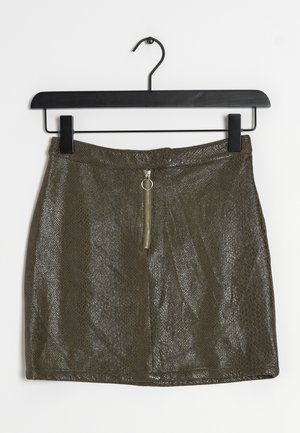 Olivgrüner Minirock mit strukturiertem Schlangenprint-Muster, ausgestattet mit einem Frontreißverschluss und einem Ring-Zipper-Detail, hängt an einem schwarzen Kleiderbügel.