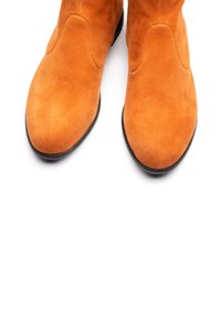 Stivali da cowboy in suede di un vivace arancione, con punta affusolata e dettagli di cucitura sottili, dotati di una sottile suola in gomma nera per una migliore aderenza.