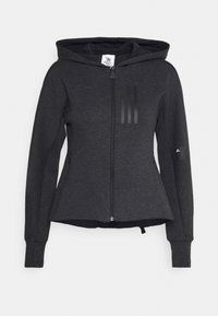Un hoodie noir zippé avec une forme péplum, comportant une capuche, un tissu texturé et trois rayures verticales sur la poitrine. Logo sur la manche.