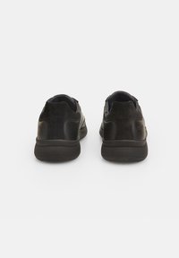 Black athletic shoes with a mix of leather and suede textures, rounded shape, low-top design, and perforated rubber soles.