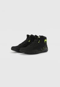 Black high-top sneakers with mesh and synthetic materials. Features bright green accents and a textured rubber sole. Lace-up closure.