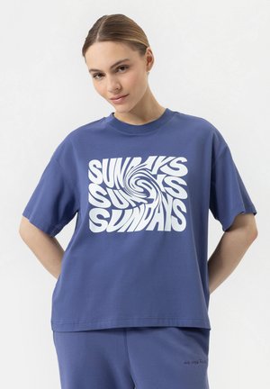 Lila übergroßes T-Shirt aus Baumwolle mit kurzen Ärmeln. Mit weißem Spiralschriftzug "SUNDAYS" in einer kräftigen, spielerischen Schriftart.