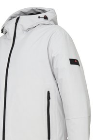 Giacca grigia chiaro con cappuccio, zip nera e tasche, con un accento sulla manica nera con logo. Materiale liscio e impermeabile.