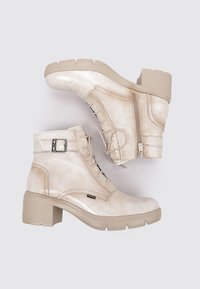 Botines beige con acabado brillante, cordones en la parte delantera, cremallera lateral y un tacón grueso beige. Presentan un acento de hebilla plateada.