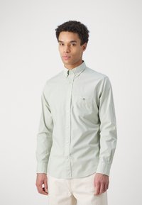 Light green button-up shirt made of cotton with a single chest pocket, featuring a collar and long sleeves.