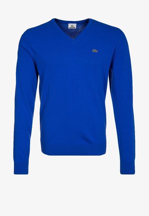 Pull bleu à manches longues avec col en V et logo Lacoste brodé sur la poitrine gauche.
