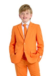 Completo arancione realizzato in tessuto liscio, comprende un blazer con due bottoni, una cravatta abbinata e pantaloni separati, su uno sfondo bianco.