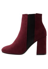 Bota de ante granate hasta el tobillo con tacón ancho, panel lateral elástico negro, suela en ángulo y punta redondeada.