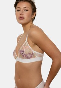 Soutien-gorge avec des bonnets en dentelle florale transparente, en pêche, violet et beige, présentant une délicate broderie et un bandeau blanc. Bretelles ajustables pour un meilleur ajustement.
