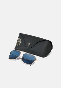 Sončna očala Ray-Ban z modrimi lečami in zlatim kovinskim okvirjem, v kompletu z črnim, strukturiranim etuijem z logotipom in zapiranjem na pritisni gumb.
