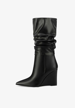 Stivali con tacco a zeppa in pelle nera, con un gambale morbido e punta affusolata, caratterizzati da una superficie liscia e un design elegante e strutturato.