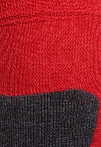 Tessuto lavorato a maglia rosso e grigio scuro con una texture a coste; presenta una cucitura orizzontale distintiva dove si incontrano i colori. Adatto per abbigliamento o accessori.