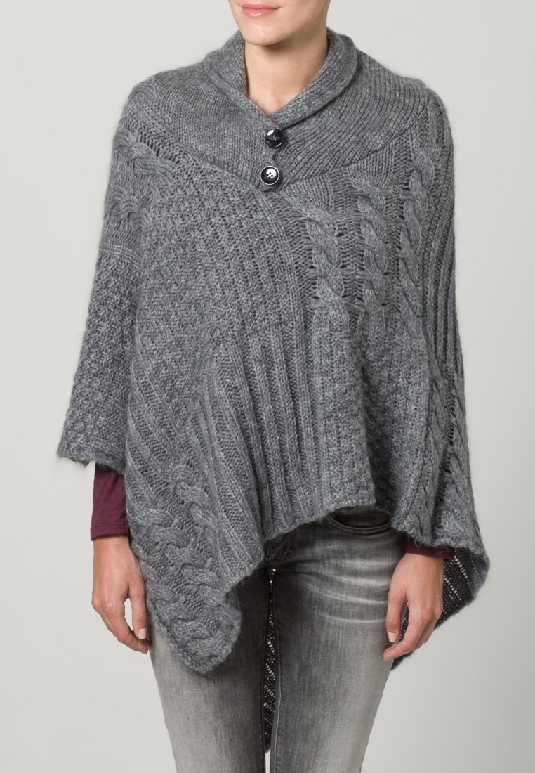 Grå stickad poncho med sjalkrage, två svarta knappar, kabelmönster och asymmetrisk fåll. Texturerat tyg med ribbmönster.