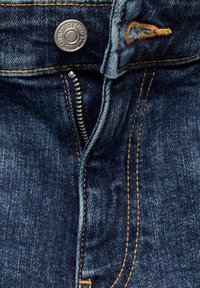 Tmavě modré denimové džíny s zipovým zapínáním a kovovým knoflíkem. Švy jsou v kontrastní oranžové barvě, což zvýrazňuje švy.