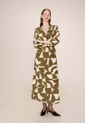 Robe longue à motifs présentant des formes abstraites en vert olive et crème. Confectionnée en tissu léger, elle possède un col en V et des manches bouffantes.