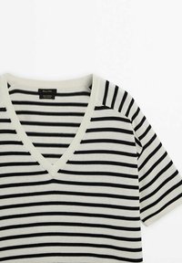 Koszulka polo w paski w kolorze kremowym i czarnym, wykonana z miękkiej bawełny, z krótkimi rękawami oraz luźnym krojem, z kontrastowym ściągaczem przy dekolcie.