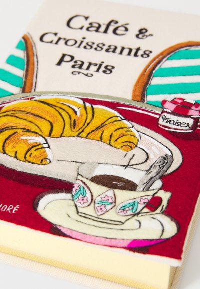 Close-up of fabric artwork showing a croissant on a plate, a floral teacup with coffee and spoon, and the text "Café & Croissants Paris."