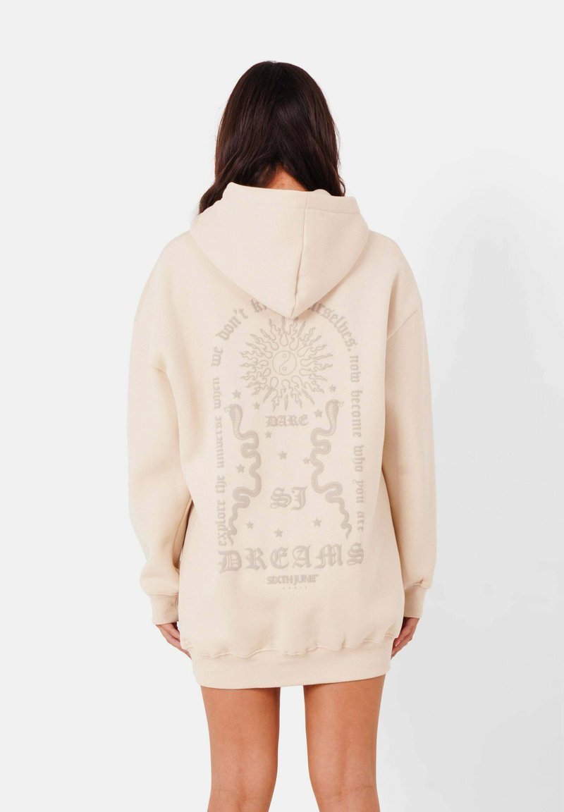 Sudadera de gran tamaño color crema hecha de una tela suave, con un estampado gráfico en la parte posterior que presenta motivos de sol y serpiente, y acentos de texto.