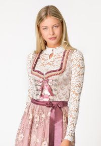 Traditionelles Dirndl mit einem rosa Spitzenoberteil, verziert mit silbernen Beschlägen und Ripsbanddurchzügen, einem floralen Tüllrock und einem satinähnlichen Gürtel mit Schleife.
