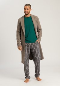 Bruine lange cardigan, groene ronde hals shirt en geplaid pyjamabroek in tinten blauw, grijs en bordeaux. Gladde stof met een relaxte pasvorm.