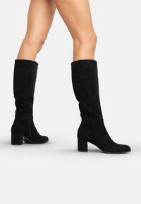Botas altas negras de ante, con cremallera lateral, tacón ancho y un diseño simple y liso sin adornos.