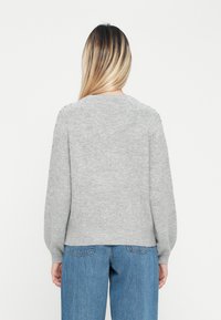 Suéter cinza de malha com gola redonda, mangas longas, punhos e barra canelados, apresentando um ajuste ligeiramente relaxado e uma textura suave.