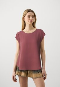 Kurzärmliges Oberteil in Mauve mit runder Ausschnitt und glatter Textur. Kombiniert mit einem gefältelten, mehrfarbigen Rock.