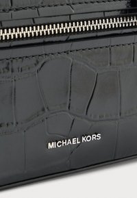 Borsa in finta pelle nera con texture a coccodrillo, zip argentata e nome del brand "MICHAEL KORS" imbottito in lettering metallico.