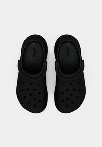 Tamancos pretos leves feitos de material flexível com furos de ventilação, alça traseira e palmilha texturizada. Vista superior.