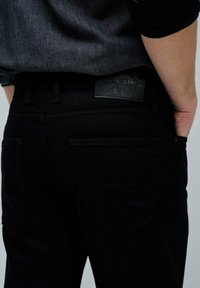 Jeans de mezclilla negros con una textura suave, que cuentan con cinco bolsillos, una etiqueta de cuero y costuras en contraste en los bolsillos traseros.