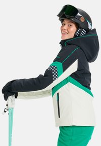 Veste de ski noire, verte et crème avec une manche à motif. Elle dispose d'une capuche, de poches zippées et d'une isolation pour le confort thermique.