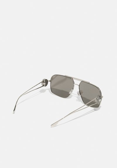 Ochelari de soare cu lentile gri și un cadru subțire din metal argintiu. Au lentile unghiulare și accente decorative pe brațele ochelarilor.