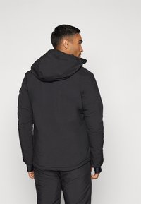 Schwarze, gefütterte Jacke mit Kapuze, glatter Textur, verstellbarer Kapuze und zwei Seitentaschen, die ein stromlinienförmiges Design für Wärme bietet.