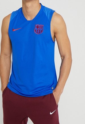 Débardeur de sport bleu avec écusson du FC Barcelone et virgule Nike rouge, porté avec un pantalon Nike bordeaux avec logo blanc.