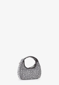 Sac à main noir et blanc de forme arrondie, orné de rivets circulaires, avec une anse courbée et une fermeture zippée.