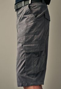 Graue Cargo-Shorts aus weichem Stoff, mit mehreren Taschen, genähten Details und geradem Schnitt. Gürtelschlaufen sind sichtbar.