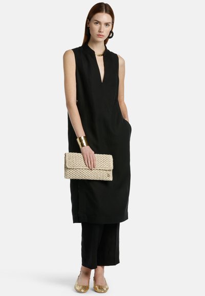 Black sleeveless dress with a deep neckline, paired with a braided beige clutch and gold flat shoes. Simple, elegant design with pockets.